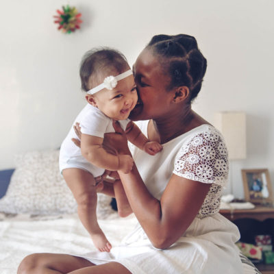 woman holding and kissing a laughing baby