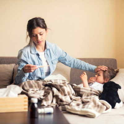 woman checking the temperature of a sick child