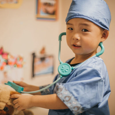 a young boy dressed up like a physician with a toy stethoscope