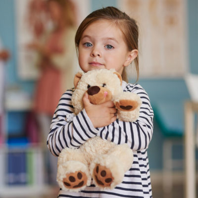 young girl hugs her stuffed bear